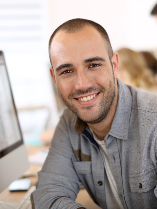 Cheerful,Guy,Sitting,In,Front,Of,Desktop,Computer